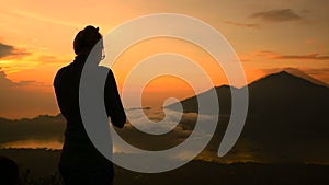 Girl taking pictures of sunrise over Lake Batur, Volcano Agung and Abang, Bali