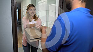 Girl taking pizza in box, paying dollars to man, satisfied with timely delivery