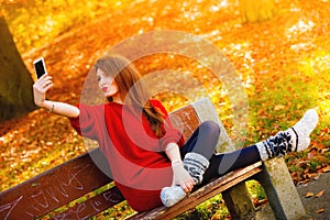 Girl taking self picture selfie with smartphone camera outdoors