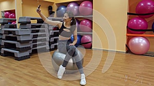 Girl taking selfie at the gym on a pilates ball.