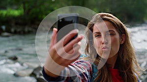 Girl taking selfie on mobile phone. Joyful woman making funny grimaces at camera