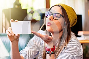 Girl taking selfie and sending air kiss.