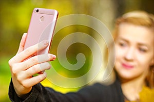 Girl taking a selfie on smart phone in autumn park