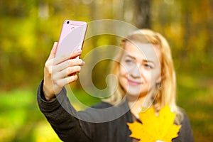 Girl taking a selfie on smart phone in autumn park