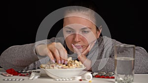 Girl taking spoon to eat tablets from bowl, pharmaceutical products