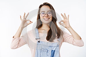Girl taking things under control assuring plan goes okay showing ok gesture and smiling in approval, saying nothing