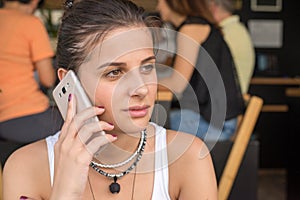 Girl talk to the smart phone in a coffee shop. Mild smile on the face