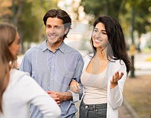 Girl Talking With Married Couple Of Friends Walking Outside