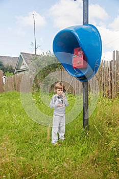 Girl talking on an old phone while standing in the middle of the street