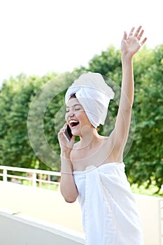 The girl is talking on the phone after a shower on the balcony