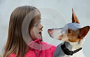 Girl talks to her  podenco. The dog listens attentively