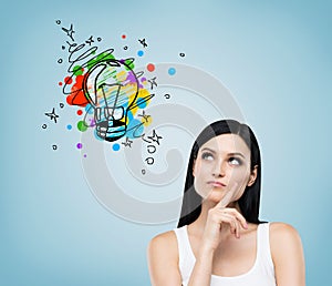 Girl in tank top looking at light bulb on blue wall