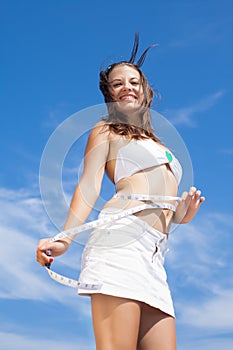 Girl with tape-measure on background of sky