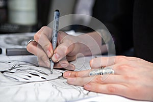 Girl tattoo artist draws a sketch. Close-up of hands