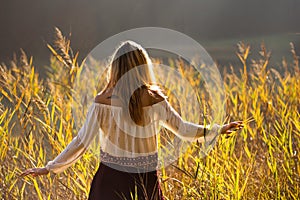 Girl with tattoo mountains on the shoulder standing and meditating in field of reeds / Blond girl walking through field of reeds