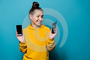 Girl taunts old cell phone holding a modern smartphone