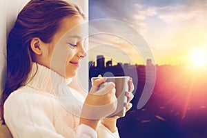 Girl with tea mug sitting at home window