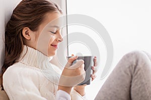 Girl with tea mug sitting at home window