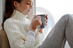 Girl with tea mug sitting at home window