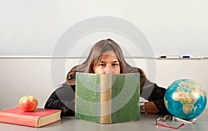Girl teacher hiding behind book