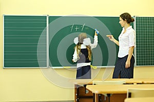 Girl and teacher near chalkboard solve simple math photo