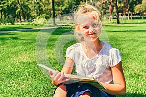 A girl teaches assignments on textbooks and sits on the green gr