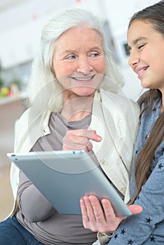 Girl teaching grandmother how to use tablet