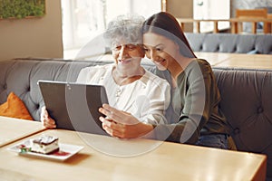 Girl teaching her grandmother how to use a tablet