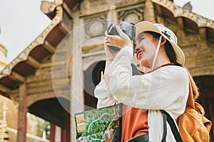 Girl teen backpacking, cultural tourism, take pictures of magnificent architecture in Thai temples