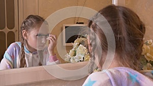 Girl teenager applying mascara on eyelashes front mirror in bedroom. Young girl using eyelashes mascara for makeup front