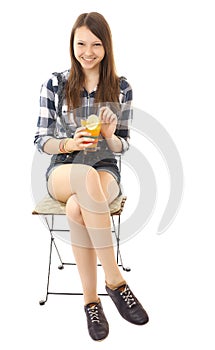 Girl teenager, caucasian appearance, brunette, wearing a plaid shirt and short denim shorts, holding a glass of drink. Girl is rel