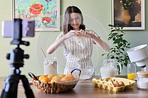 Girl teenager food blogger cooking orange pancakes at home in kitchen