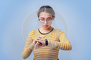 Girl teenager in glasses looks at the clock