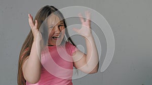 Girl teenager on a gray background depicts emotions