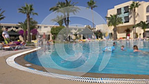 Girl teenager jumping in water swimming pool in hotel. Happy girl in glasses in swimming outdoor pool. Slow motion