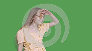 Girl teenager looking far away on transparent green background. Young girl in yellow glasses and dress peering into