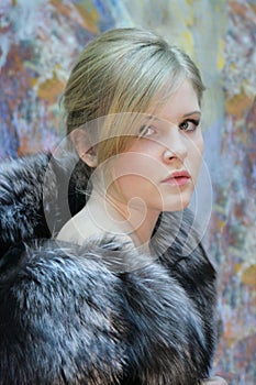 Girl - teenager, natural blonde in a chic fur coat from silver fox