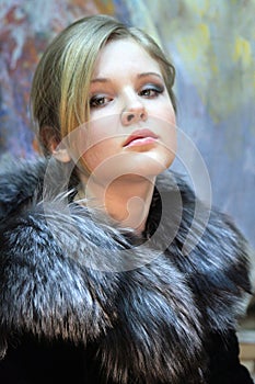 Girl - teenager, natural blonde in a chic fur coat from silver fox