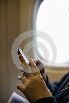 Girl teenager`s hands using a smartphone on the airplane.