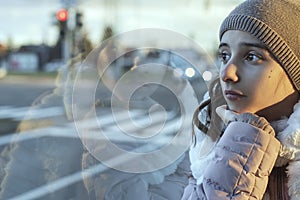 Girl teenager sits on the bus and looks out the window,teenager girl is sitting in the bus looking forward thinking.