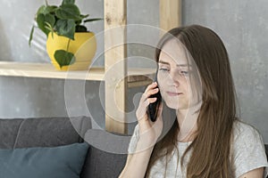 Girl teenager talking on phone sitting on couch in living room. Telephone call