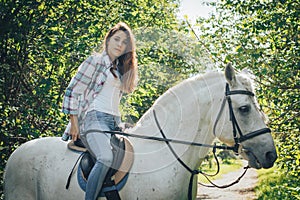 Girl teenager and white horse in a park in a summer