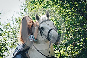 Girl teenager and white horse in a park in a summer