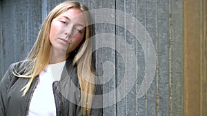 Girl teenager young woman looking sad or thoughtful wearing a green jacket in an urban city environment