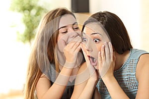 Girl telling secrets to her amazed friend photo