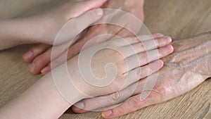 Girl tenderly stroking old hands of her granny, love and respect family relation