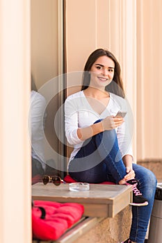 Girl text message on the phone on the window of street coffee shop