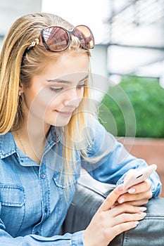 Girl texting on the smart phone in a shpping mall sitting in internet free zone photo