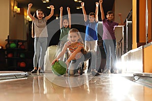 Girl throwing ball and spending time with friends in bowling