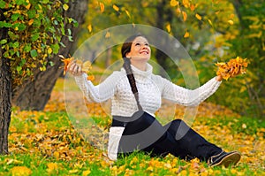 Girl throwing dry autumn leaves in the air